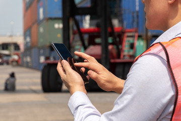 Shipping officer using smart phone  at the container yard.