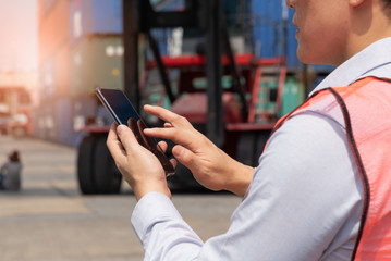 Shipping officer using smart phone  at the container yard.
