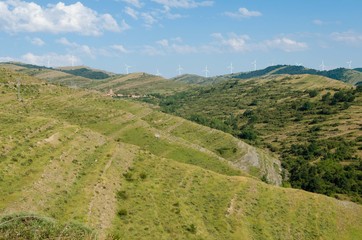 Obraz premium Village in the mountain with wind turbine or windmill providing renewable energy