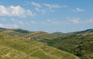 Village in the mountain with wind turbine or windmill providing renewable energy