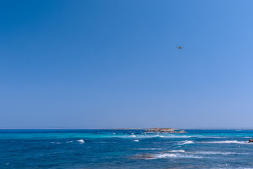 Obraz premium Seascape with beautiful blue sea and white waves in the distance lighthouse, seaplane in the air flies to the island of Formentera. Ibiza. Balearic Islands, Spain