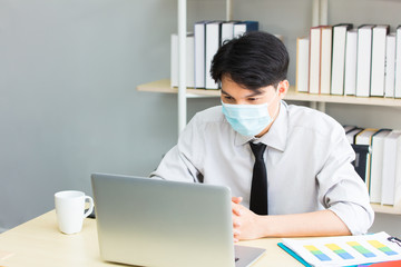 Male worker wearing a mask works with a laptop