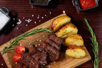 Beef shashlik garnished with vegetables and baked potatoes. In the background are sauces for meat. Top view.