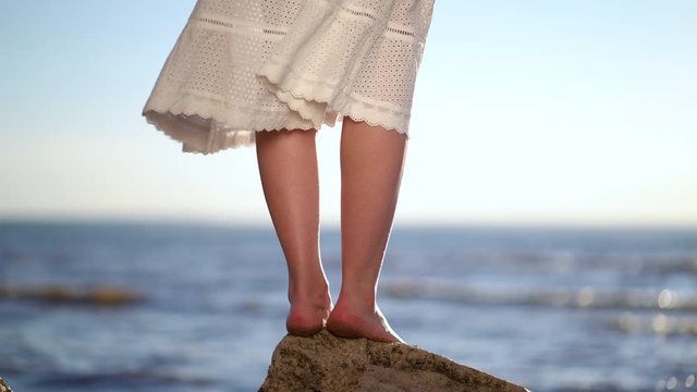 Female feet standing on a stone on the bech. Woman on the stony beach on the sea