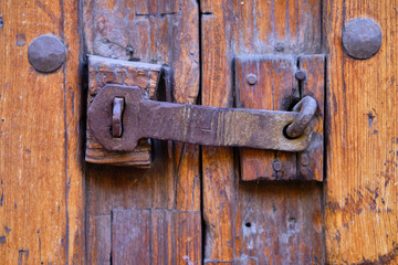 Old vintage scratched metal latch against textured door, closind door