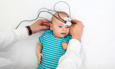 Newborn hearing screening and diagnosis at the hospital. Baby having hearing screening with special...