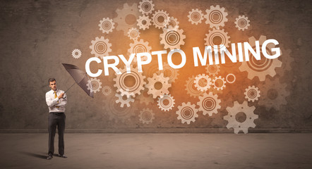 Obraz premium Businessman defending with umbrella from CRYPTO MINING inscription, technology concept