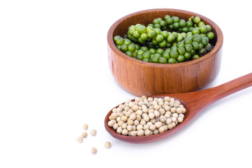 Closeup fresh green pepper in wooden bowl and white peppercorn seeds ( piper nigrum)  in spoon isolated on white background. 
