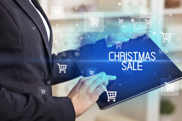 Young person makes a purchase through online shopping application with CHRISTMAS SALE inscription