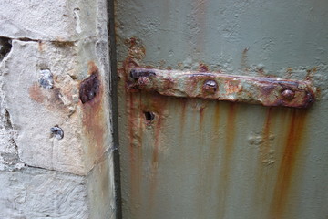Extrem rostige metallene Türverriegelung. Lange braune Korrosionsstreifen durch zu viel Regen und Feuchtigkeit. Heavy rusty iron door and copper irony.
