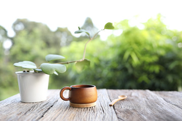 Wooden cup and spoon with Hoya kerri plant pot on old wood table