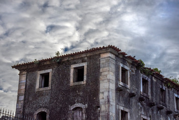 Fototapeta na wymiar Multi-Windowed Abandoned Stone Monastery With Ominous Clouds, Braga, Portugal