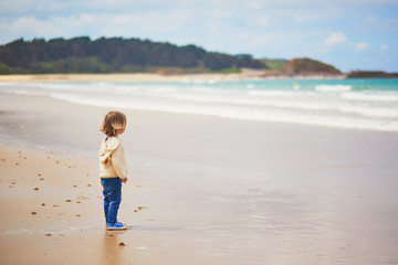 Fototapeta na wymiar Adorable toddler girl on the sand beach at Atlantic coast of Brittany, France