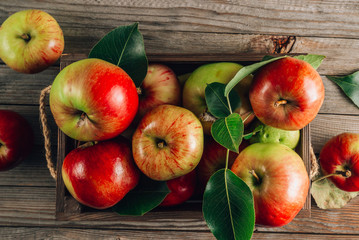 Fresh organic green and red apples in the wooden box. On rustic wooden background.