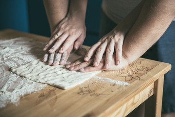 Preparing pizza dough. Young couple makes pizza for dinner. Romantic dinner. Cooking pizza at home. Rolling pin and flour on the table. Woman's and  man's hands together.