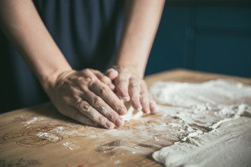 Obraz na płótnie Canvas Preparing pizza dough. Young couple makes pizza for dinner. Romantic dinner. Cooking pizza at home. Rolling pin and flour on the table. Woman's and man's hands together.
