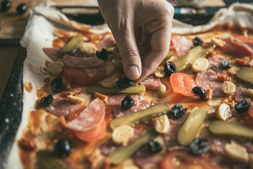 Woman cuts oliva on a cutting board. The stage of preparing pizza products. The lifestyle of a modern young family.