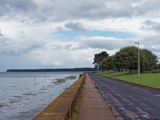 Looking down the small Promenade Road at Tayport passing by Tayport Common, with Tentsmuir Forest in the distance on a wet day in August.