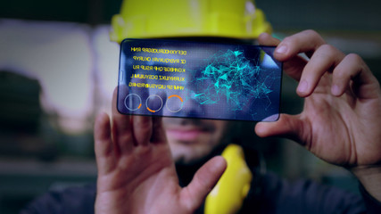 Factory worker use future holographic screen device to control manufacturing machine in factory . Concept of futuristic automation technology , virtual augmented reality and smart visualization .