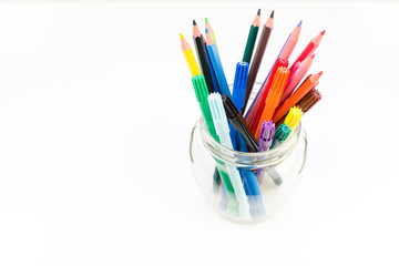 Artist's set. Colored pencils and felt-tip pens lie in purple a jar on a white background