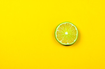 Fresh lime slice on bright yellow background