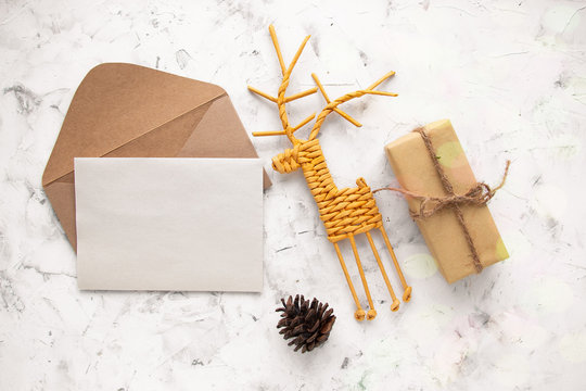 Craft kraft paper envelope with blank letterhead, fir cone, vine deer and gift on light background flat lay top view