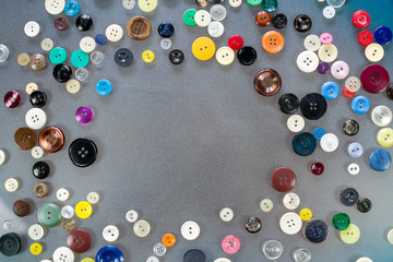 Many multi-colored buttons lie on the table, forming an empty space in the middle