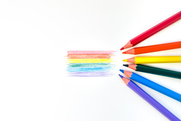 Lgbt rainbow flag on white background and colored pencils of all colors of the rainbow adjoining their color