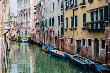 Fototapeta na wymiar Canal between old houses with blue boats in the city Venice. Italy.