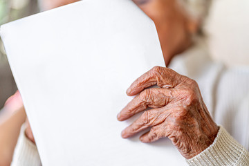 Nahaufnahme Hand, alte Frau mit faltigen Händen liest einen weißen Brief