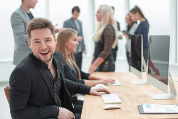 young man and his colleagues sitting at an office Desk.