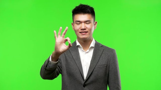 Young chinese business man cheerful and confident doing ok gesture