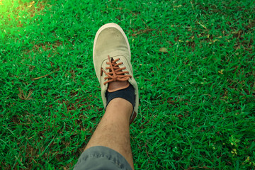 The left foot stepped on the green grass with an orange light in