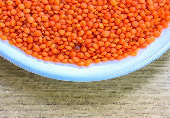 Red lentils in a round white plate: ingredients for a healthy diet natural meal