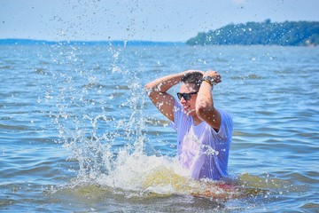 portrait of a handsome man splashing water in the sea