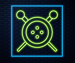 Glowing neon line Sewing button and knitting needles icon isolated on brick wall background. Clothing button. Vector Illustration.