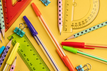 Colorful school stationery items on a yellow background. Top view. Concept back to school