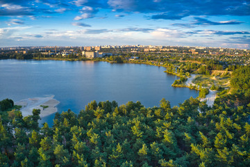 Fototapeta na wymiar Lake near the forest and the city in the background