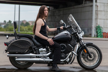 Plakat Long-haired guy on a black motorcycle under the bridge