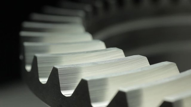 Close-up of a rotating gear wheel in machinery &ndash; dark grey color