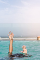 Women's hands coming out of the pool water.