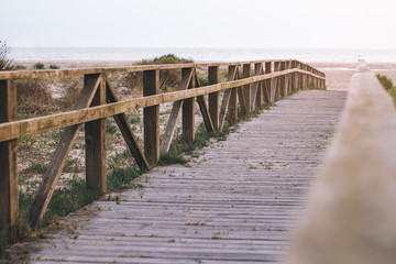 Fototapeta premium Wooden path at Atlantic Ocean over sand dunes with ocean view, sunset summer evening.