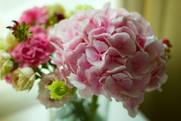 Bouquet of pink flowers in  glass vase on  white table. Spring or summer greeting card with flowers. Mother's Day Greeting Card. Happy Birthday or Valentine. Women's Day. Copy space.