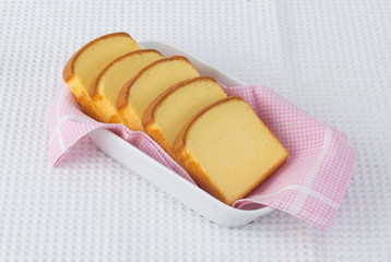 Sliced butter cake on white dish on white cloth background