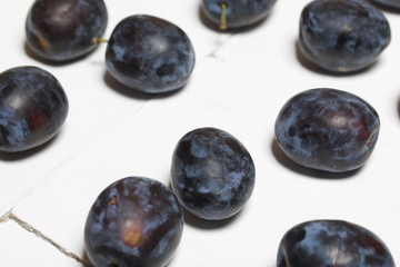 Ripe plums. Scattered on a white surface.