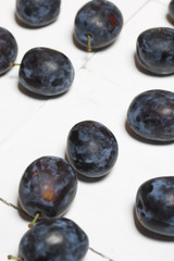 Ripe plums. Scattered on a white surface.