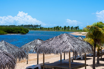 V&aacute;rios quiosques na praia com uma ilha ao fundo