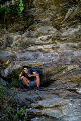 Young boy showing thumbs up into the camera from a height, after climbing a huge rock.