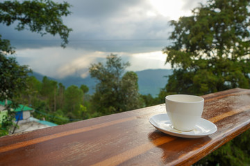 Cup with tea on table over mountains landscape with clouds. Beauty nature background