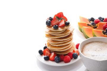 Breakfast with pancakes with berries and honey, coffee and fruit isolated on a white background, copy of space